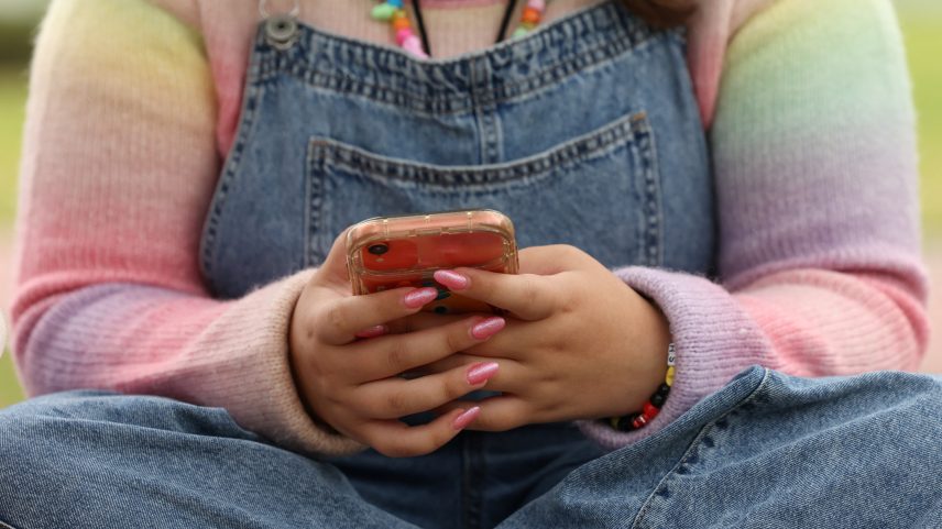 Jovem usa o celular em Sidney, na Austrália; país aprovou lei que proíbe acesso de menores de 16 anos às redes sociais — Foto: Hollie Adams/Reuters