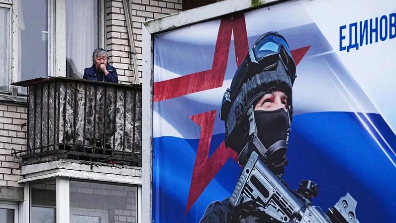 A woman stands on a balcony of an apartment building in St. Petersburg, Russia.