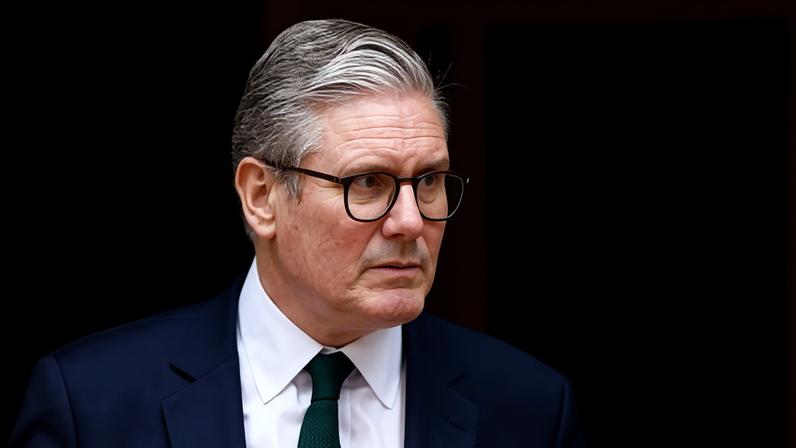 Keir Starmer outside No 10, wearing a dark jacket and tie, looking sombre.
