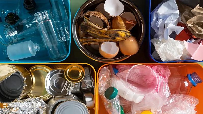 Fotografia de recipientes de plástico multicoloridos enchendo com diferentes tipos de resíduos e lixo, como alimentos orgânicos, papel, plástico, estanho