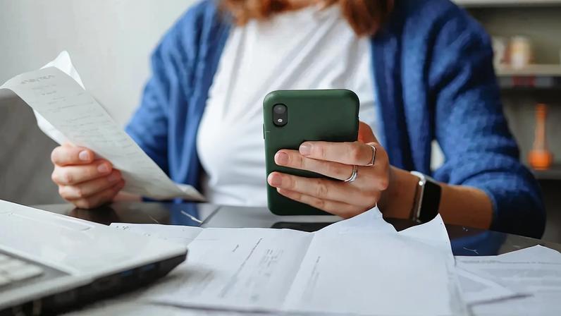 Uma mulher olhando boletos com um bebê no colo.