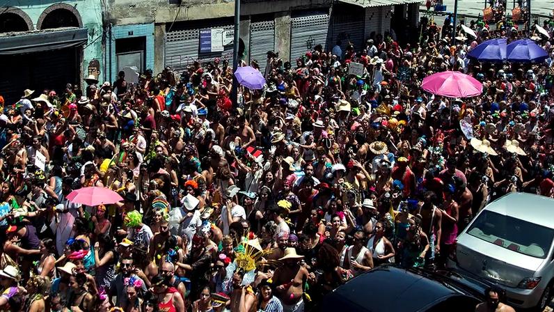 Fotografia de um bloquinho de carnaval lotado de pessoas.