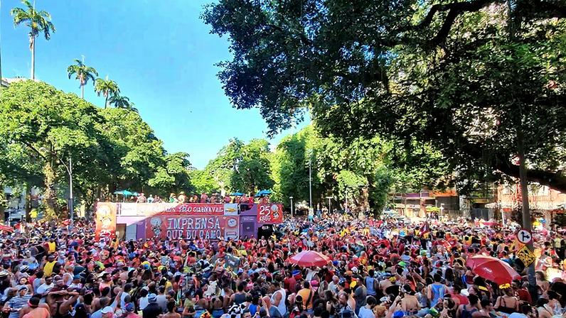 Fotografia do Carnaval de Rua no Rio de Janeiro. Imagem de um bloquinho lotado de pessoas em um dia de sol forte.