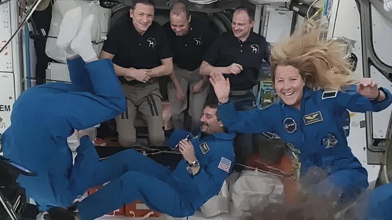 Astronauts floating about and waving onboard in the International Space Station