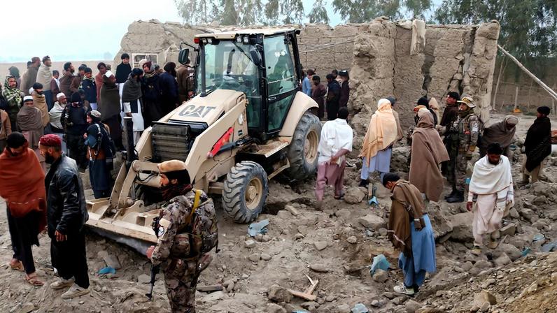 Residents gather near a damaged house as a loader clears debris, following the Pakistani airstrikes, in Bihsud district, Nangarhar province, Afghanistan, February 22, 2026.