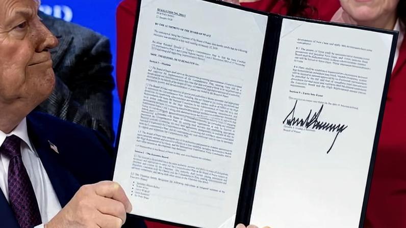 Donald Trump holds a signed resolution as he attends a charter announcement for his Board of Peace in Davos, Switzerland, on 22 January 2026.