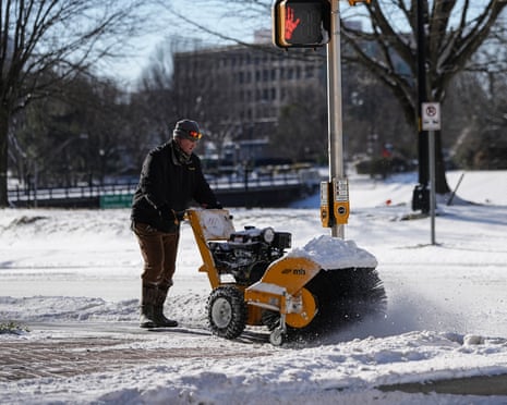 A worker uses a snowblower to help clear the sidewalk on Sunday in Charlotte, North Carolina.