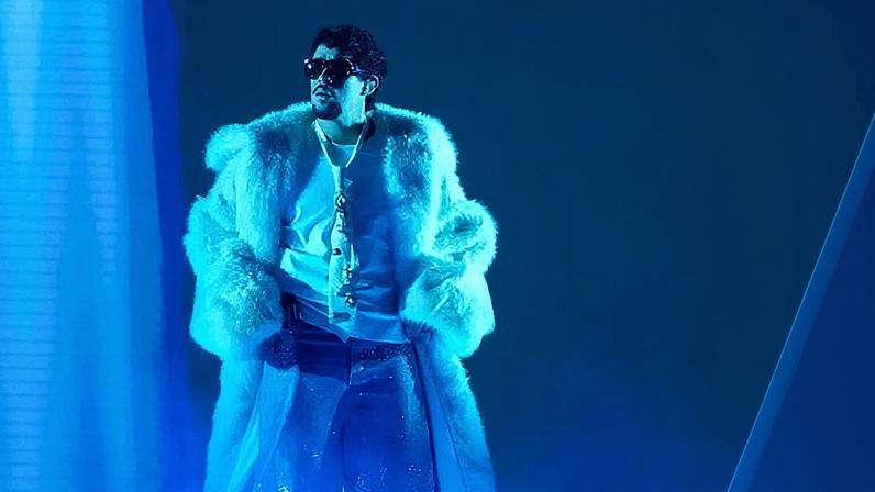 Bad Bunny on stage in a massive white fur coat