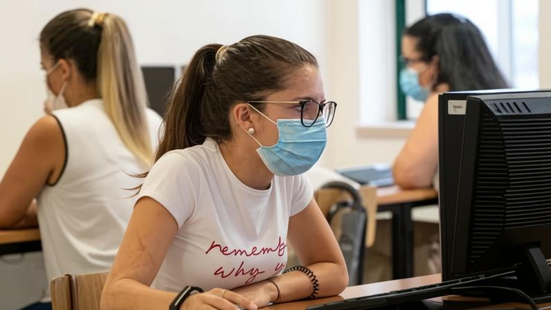 Young woman wearing mask on a computer.