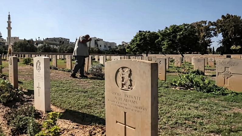 A gardener tends to the lawn between the tombstones at the Commonwealth Gaza War Cemetery in Gaza in 2022, before the outbreak of the current conflict. More than 250 Australian soldiers from world war one and world war two are buried in the graveyard.
