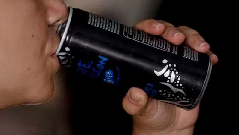 Una joven toma una lata de una bebida energética.