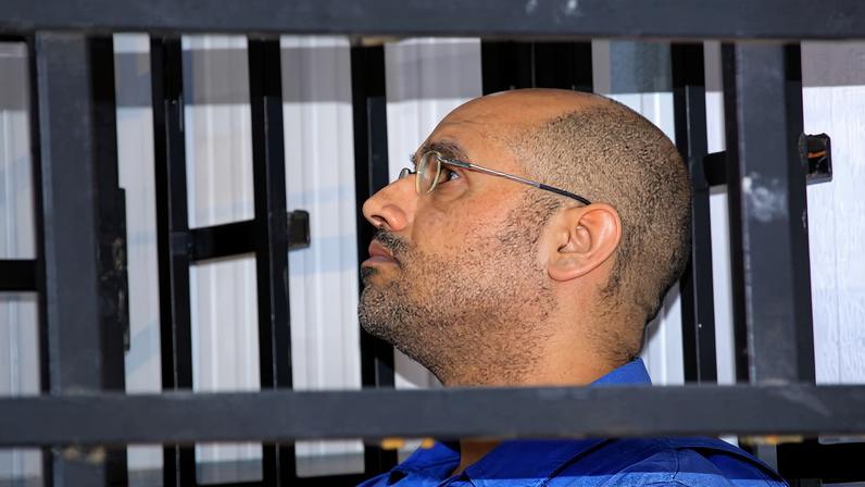 Saif al-Islam Gaddafi, son of late Libyan leader Muammar Gaddafi, attends a hearing behind bars in a courtroom in Zintan