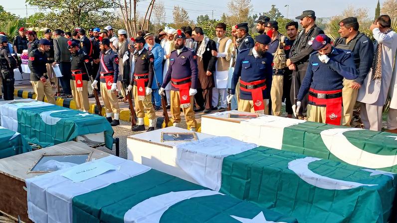 Police officers and residents gather beside Pakistani flag-draped coffins of police officers, who were killed following a terrorist attack on a police vehicle, during a funeral in Kohat