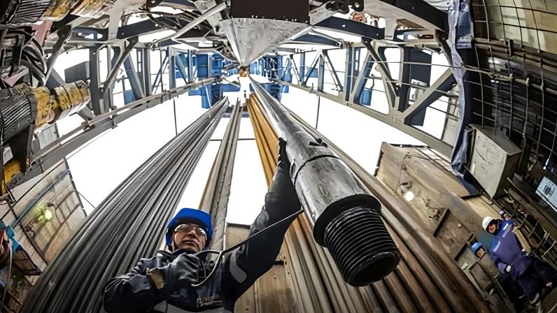 A worker guides gas-drilling pipes on a rig.