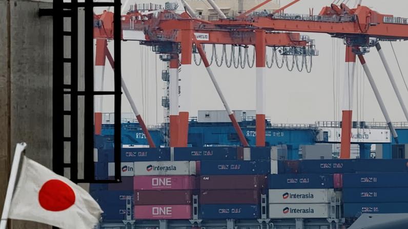 A Japanese national flag flutters in front of cargo containers at an industrial port in Tokyo, Japan, today.