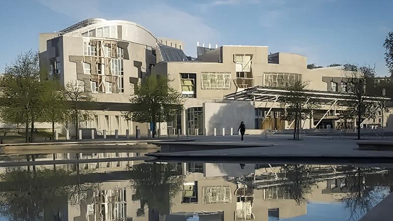 PA Media The Scottish Parliament building in Edinburgh with the building and trees reflecting on the water.