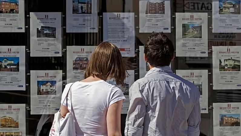 First-time buyers looking at the window of an estate agents.