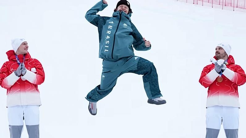Brazil's Lucas Pinheiro Braathen, flanked by the Swiss Marco Odermatt, right, and Loic Meillard, jumps for joy on winning a gold medal in the giant slalom
