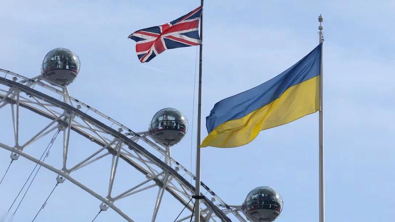 Ukraine flag and British Union flag fly from British government buildings as people ride on the London Eye wheel attraction, in London
