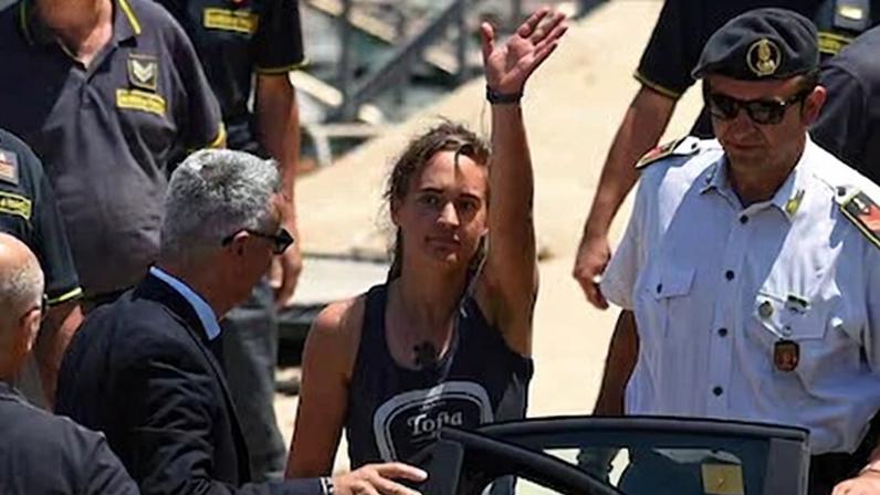 La capitana del barco de la ONG de rescate Sea Watch, Carola Rackete, saluda antes de entrar en un coche policial para prestar declaración el 1 de julio de 2019.