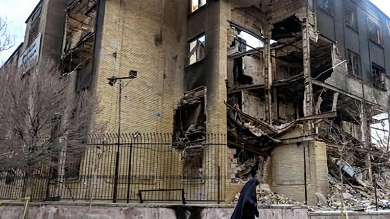 A woman walks past the remains of government building that was set on fire during protests in Tehran in January. There are unverified reports that a former Canberra boy has been killed in Iran in the wake of the January protests.
