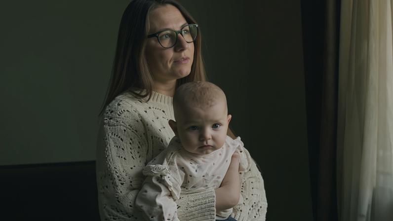 Ivanna Didur smiles as she looks out of a window while holding Anastasia