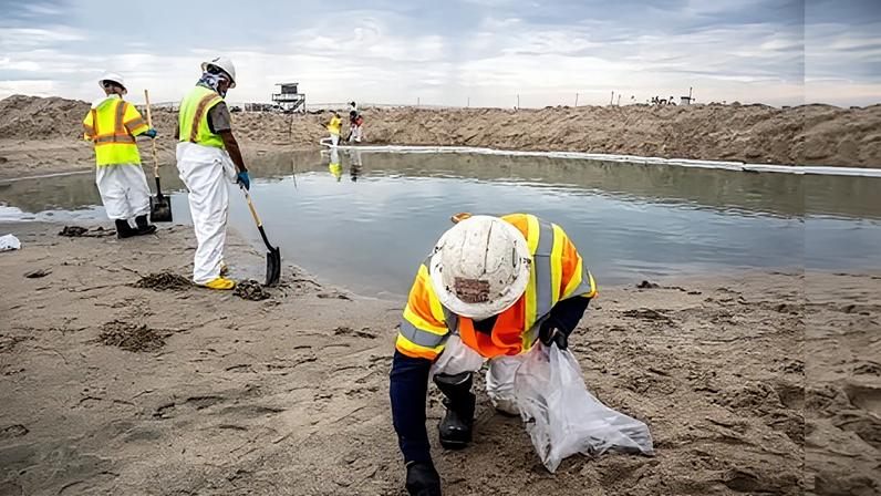A crew cleans up oil and tar blobs in Orange county, California, in October 2021.