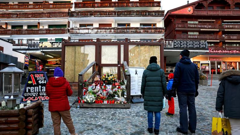 People stand by a makeshift memorial outside the "Le Constellation bar" almost a month after a deadly fire during a New Year's Eve party, in the upscale ski resort of Crans-Montana, Switzerland, January 31, 2026.