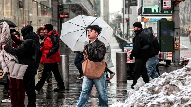 People walk on a street as snow falls during a winter storm in New York City