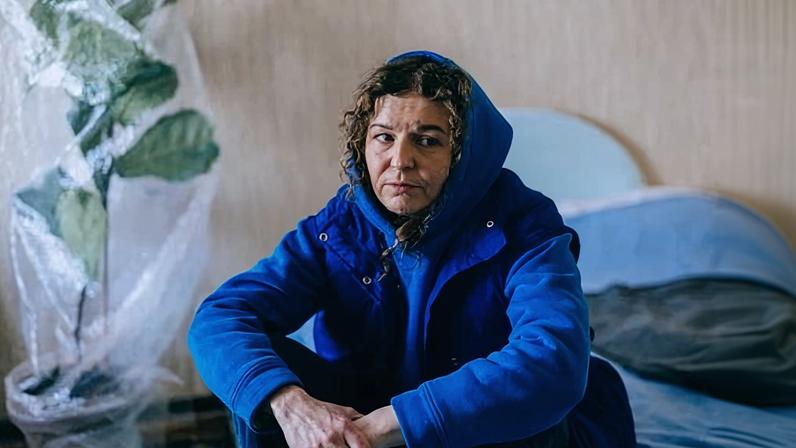 Po sitting in a coat in front of a bubble-wrapped plant