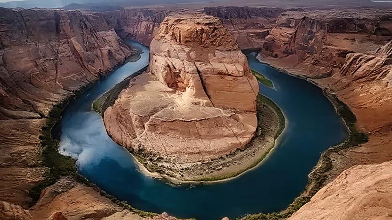 An aerial shot of a horse shoe bend of the Colorado River - the water is dark blue and the rock rusty brown.