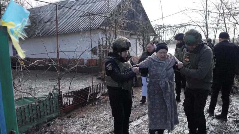 Ukrainian national police officers assist a woman during an evacuation of residents from the Tavriiske and Yurkivka villages in Ukraine's Zaporizhzhia region, amid Russia's attack on Ukraine, in this screengrab from a video, February 3, 2026.