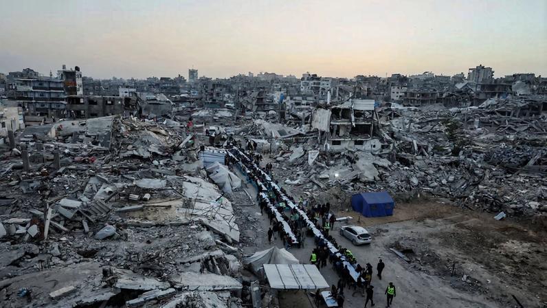 Palestinians gather to break their fast by eating Iftar meals on the first day of the holy month of Ramadan, near the rubble of residential buildings destroyed during the two-year Israeli offensive, in Gaza City