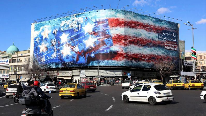 Iranianos caminham perto de um enorme outdoor anti-EUA pendurado na Praça Enqelab, em Teerã (Foto: EFE/EPA/ABEDIN TAHERKENAREH)