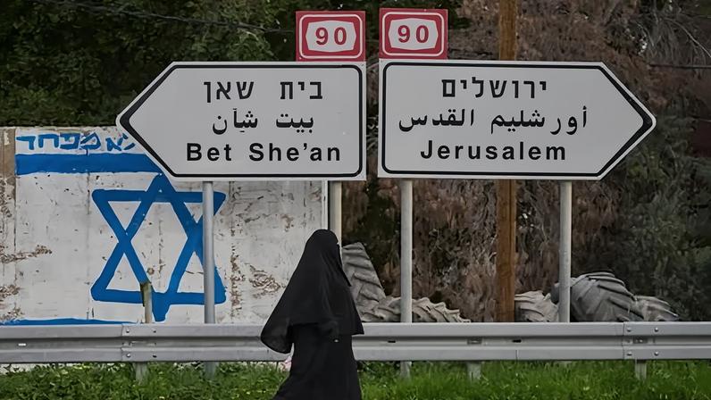 A Palestinian woman walks on the road in the Jordan Valley, in the West Bank. Israel has been criticised for its plans to increase its control over West Bank territory.