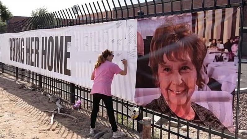 A person signs a banner that reads ‘Bring her home’ and shows a photo of Nancy Guthrie in Tucson, Arizona, on Thursday.