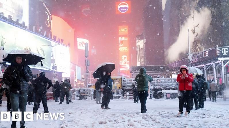 People with umbrellas in a snowy Times Square at night