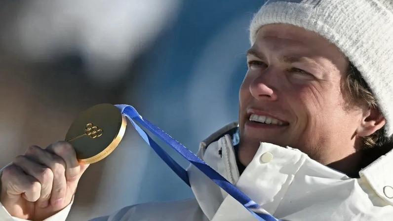 O norueguês Johannes Høsflot Klæbo comemora o ouro no pódio dos 10km livre com largada intervalada do esqui cross-country, nos Jogos Olímpicos de Inverno Milano Cortina 2026, em Tesero, em 13 de fevereiro de 2026. (Foto: Javier Soriano/AFP)