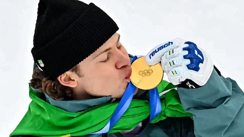 Lucas Pinheiro Braathen beija a medalha de ouro no pódio do slalom gigante masculino em 2026. (Foto: Fabrice Coffrini/AFP)