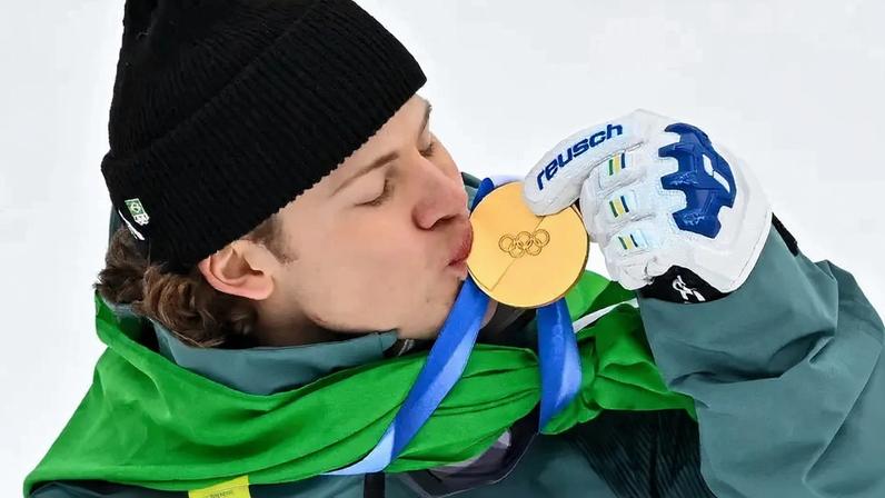 Lucas Pinheiro Braathen beija a medalha de ouro no pódio do slalom gigante masculino em 2026. (Foto: Fabrice Coffrini/AFP)