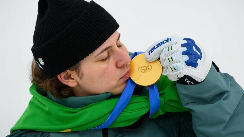 Lucas Pinheiro Braathen beija a medalha de ouro no pódio do slalom gigante masculino em 2026. (Foto: Fabrice Coffrini/AFP)