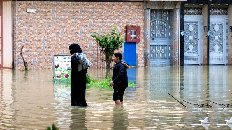 A mother and her son evacuate through a flooded street after heavy rainfall in Ksar El Kebir, Morocco, Friday, Jan. 30, 2026. (AP Photo)