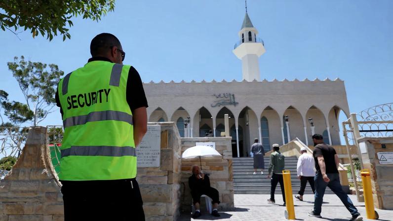 A security guard stands outside the Lakemba Imam Ali bin Abi Talib Mosque as people arrive for Friday prayers, amid a heightened security presence following the deadly mass shooting during a Jewish Hanukkah celebration at Bondi Beach on December 14, in Sydney, Australia, December 19, 2025. REUTERS/Hollie Adams/File Photo