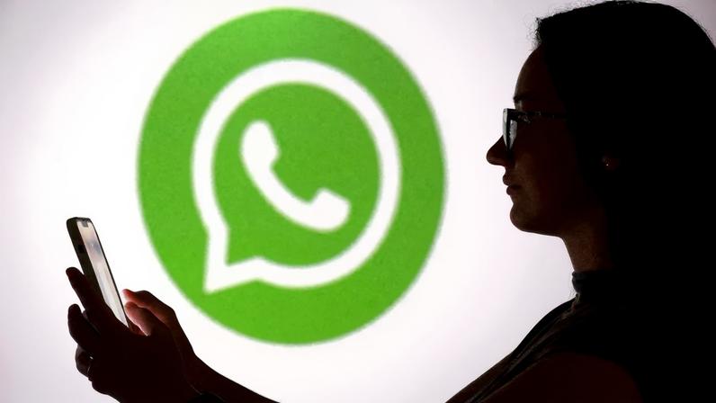 A teenager poses for a photo while holding a smartphone in front of a Whatsapp logo in this illustration taken September 11, 2025. REUTERS/Dado Ruvic/Illustration/File Photo