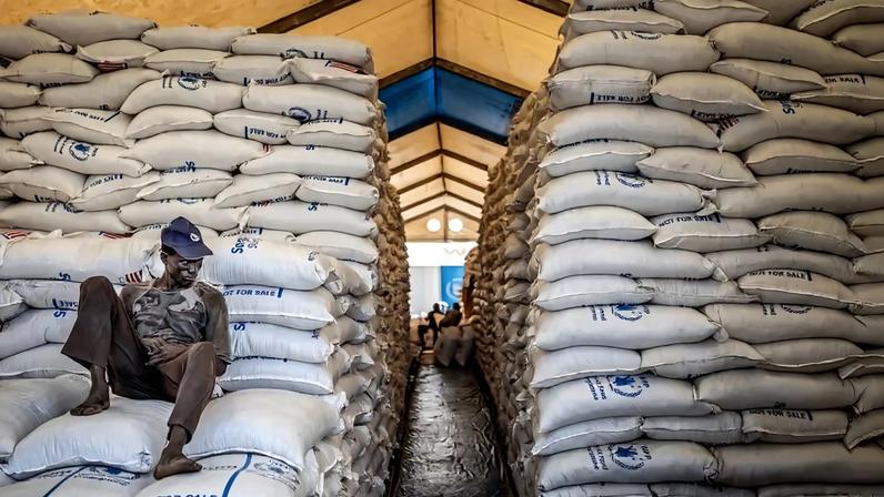 A worker sits on top of sacks of food in a hangar at a World Food Program warehouse in Bor, South Sudan, on Feb. 13. Luis Tato/AFP via Getty Images