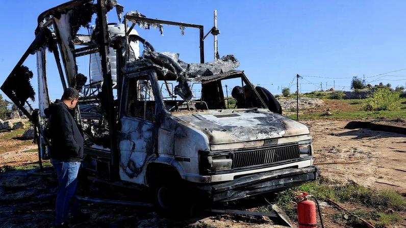 Palestinians check damage to a burned vehicle, in Susiya near Hebron