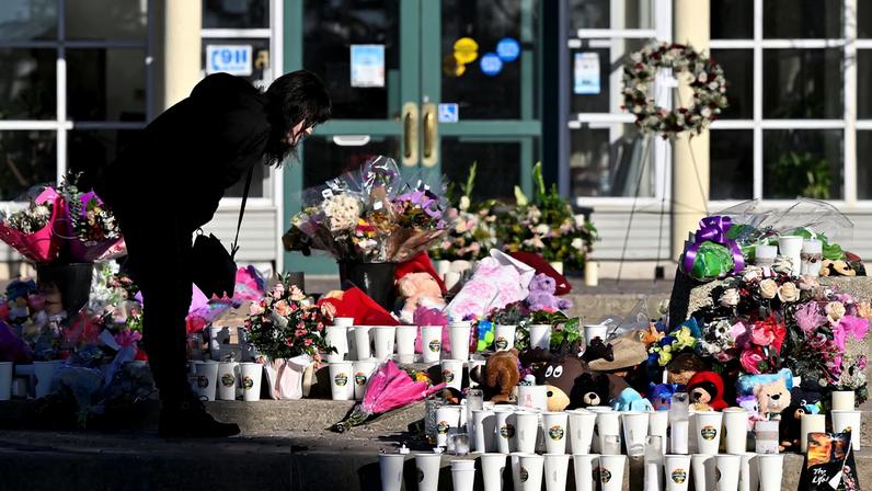 A woman visits a growing makeshift memorial on the steps of the town hall, four days after one of the worst mass shootings in recent Canadian history, in the town of Tumbler Ridge, British Columbia, Canada, February 14, 2026.