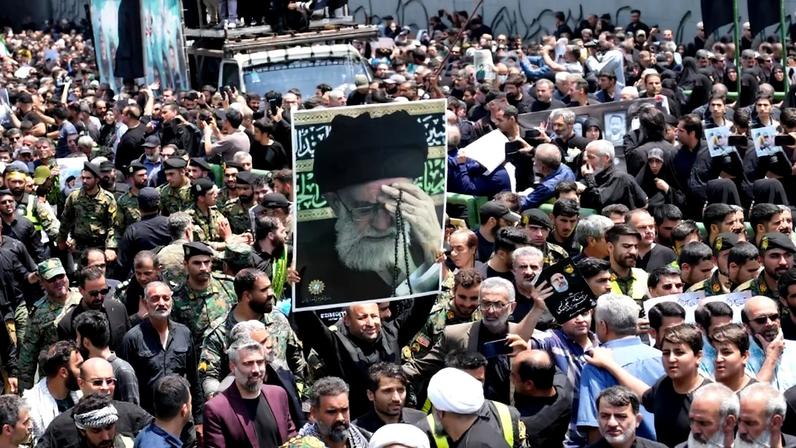 Mourners carry a portrait of Iran's supreme leader, Ayatollah Ali Khamenei, during the passage of the funeral of Iran's President Ebrahim Raisi through Tehran on May 22, 2024.