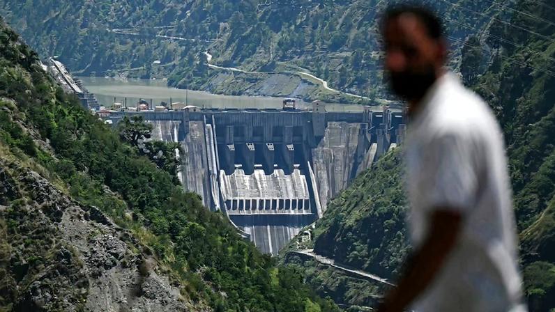 This photograph taken on May 15, 2025 shows a man walking past the Baglihar Dam, also known as Baglihar Hydroelectric Power Project, on the river Chenab in the Ramban district of Jammu and Kashmir.