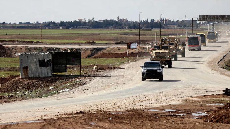 U.S. military vehicles move ahead of buses transporting Islamic State detainees from Syria to Iraq, according to a security source from the Syrian Democratic Forces, in Qamishli, Syria.